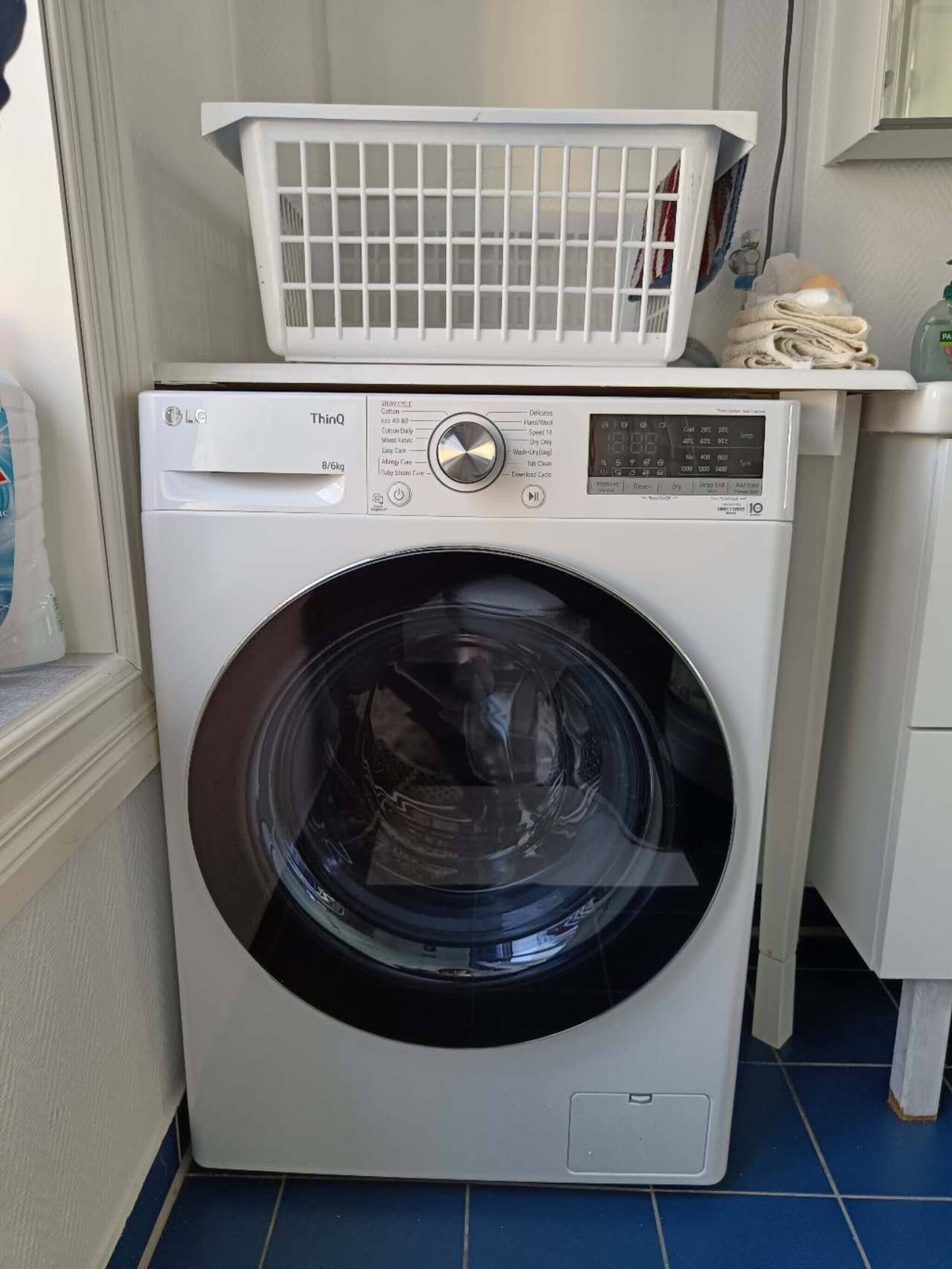 Une machine à laver à chargement frontal, dotée d’un panneau de commande et d’un panier à chargement par le dessus.