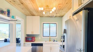A modern kitchen with white cabinets, a stainless steel dishwasher, a red microwave, and a black refrigerator.