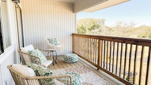 A covered outdoor seating area with wicker furniture and a view of the landscape.