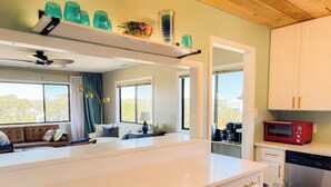 A modern kitchen with white cabinetry, a stainless steel dishwasher, a red microwave, and a coffee maker.