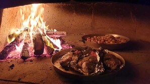 Ein traditionelles Kochfeuer mit Topf und Pfanne, in einem Topf Fleisch und in einem anderen Gemüse.