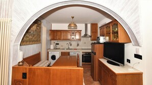Eine kompakte Küche mit Holzausstattung, Backofen, Mikrowelle und Fernseher.