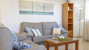 Ein Wohnzimmer mit grauem Sofa, einem Holztisch und einem Bücherregal.