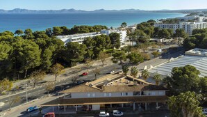 Eine Küstenstadt mit einem markanten Gebäude mit Ziegeldach, umgeben von Bäumen und freiem Blick auf das Meer.