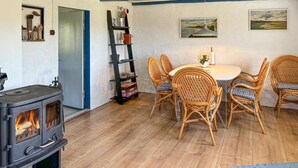 Un salon chaleureux avec un poêle à bois, des fauteuils en osier, une table à manger et une bibliothèque.