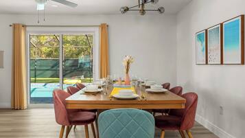 A dining area with a wooden table set for four, surrounded by red chairs.