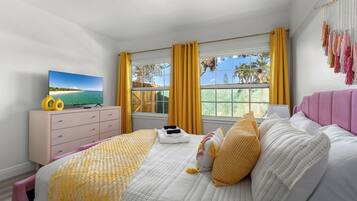 A bedroom with a bed, a dresser, a TV, and a window with curtains.