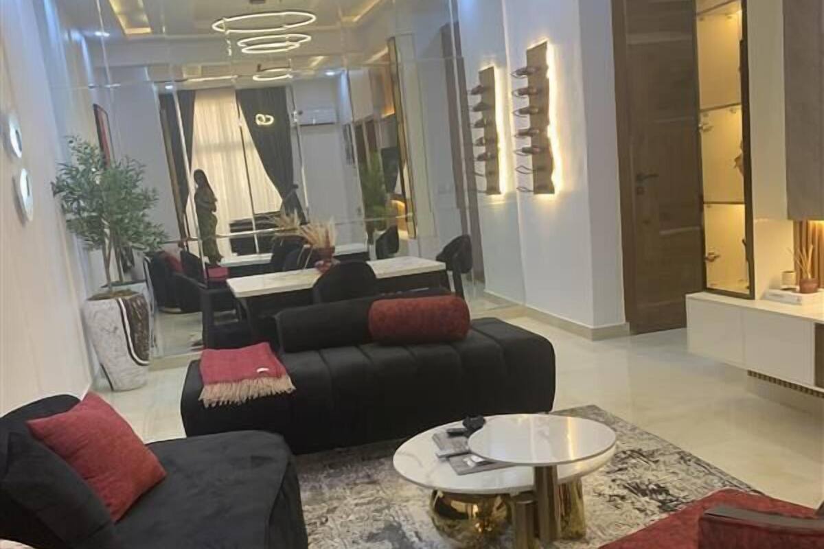 A modern living room with a black sectional sofa, a red armchair, and a round coffee table.