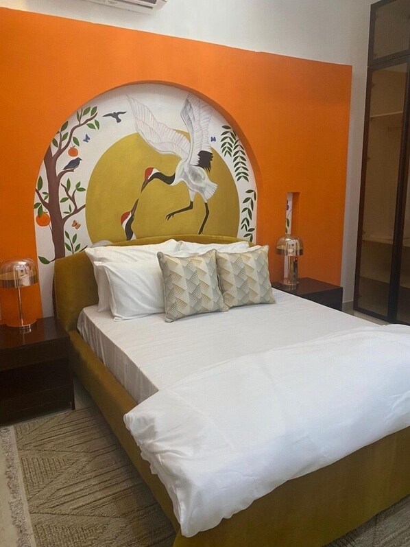 A bed with white linens, a patterned headboard, and two bedside lamps. - Spacious 2-bedroom apartment (Lekki)