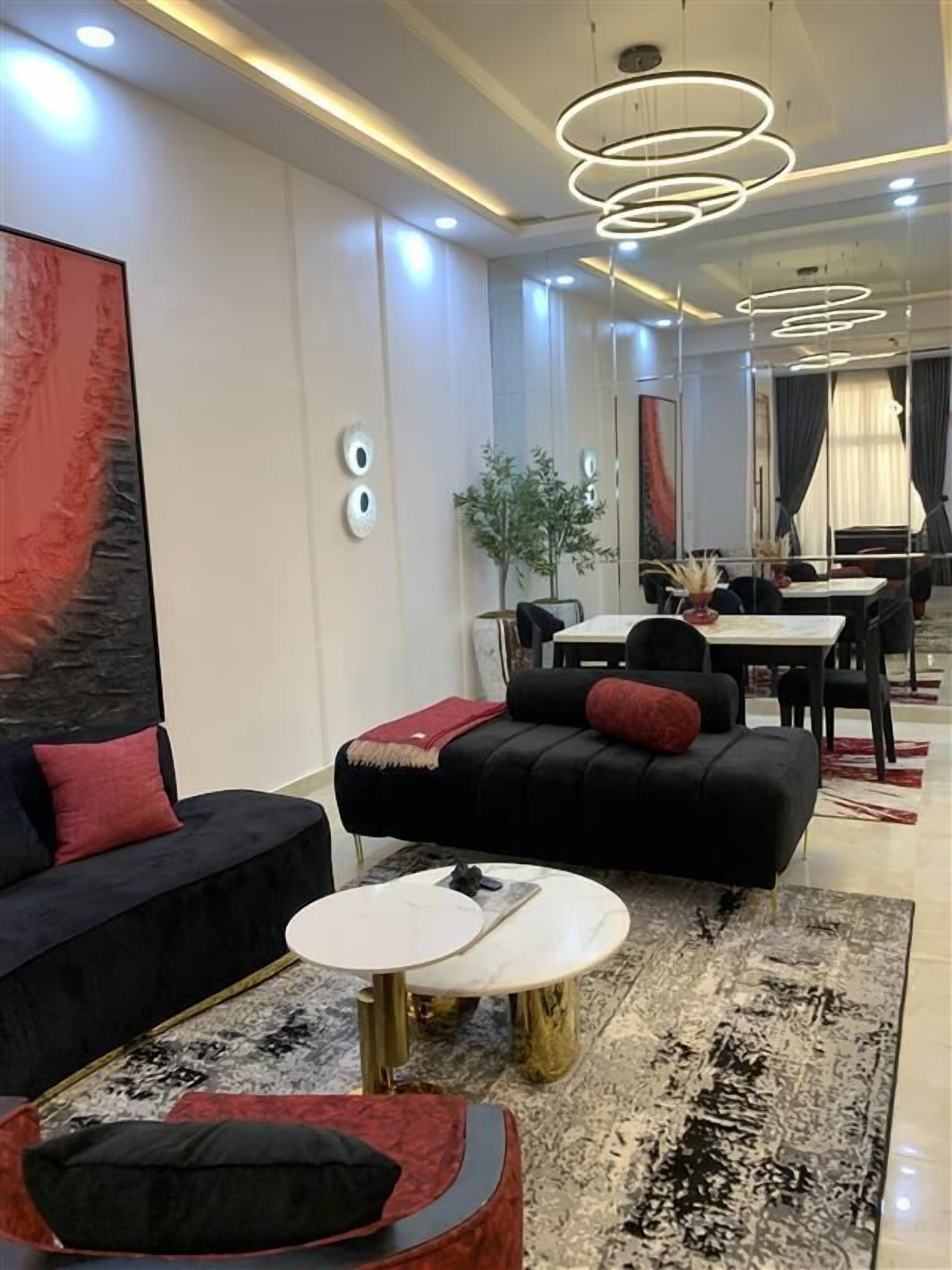 A modern living room with a black sofa, a round coffee table, and a dining area with a table and chairs.