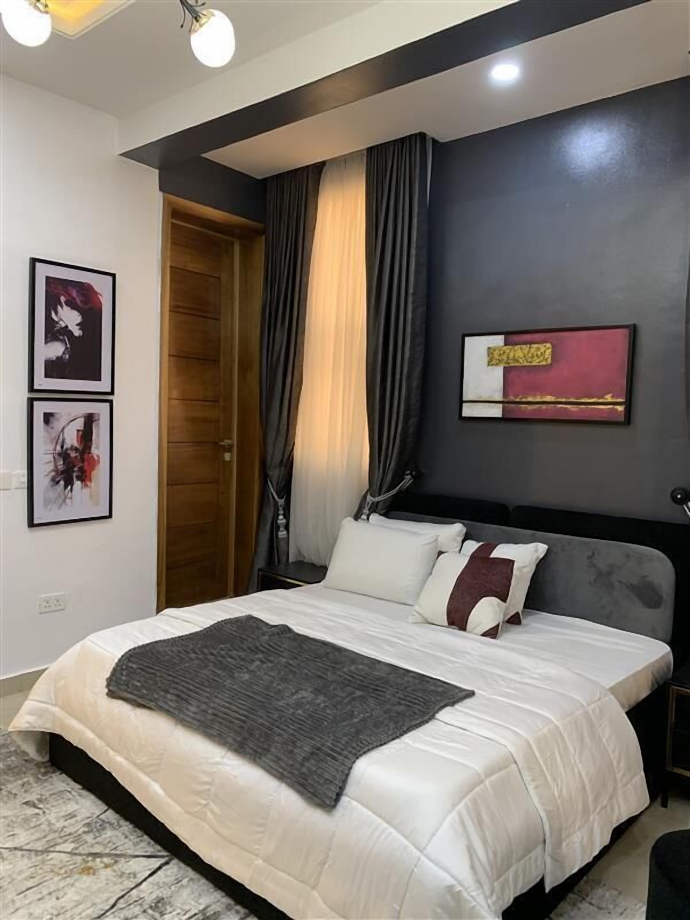 A modern bedroom with a large bed, a wooden door, and a painting on the wall.