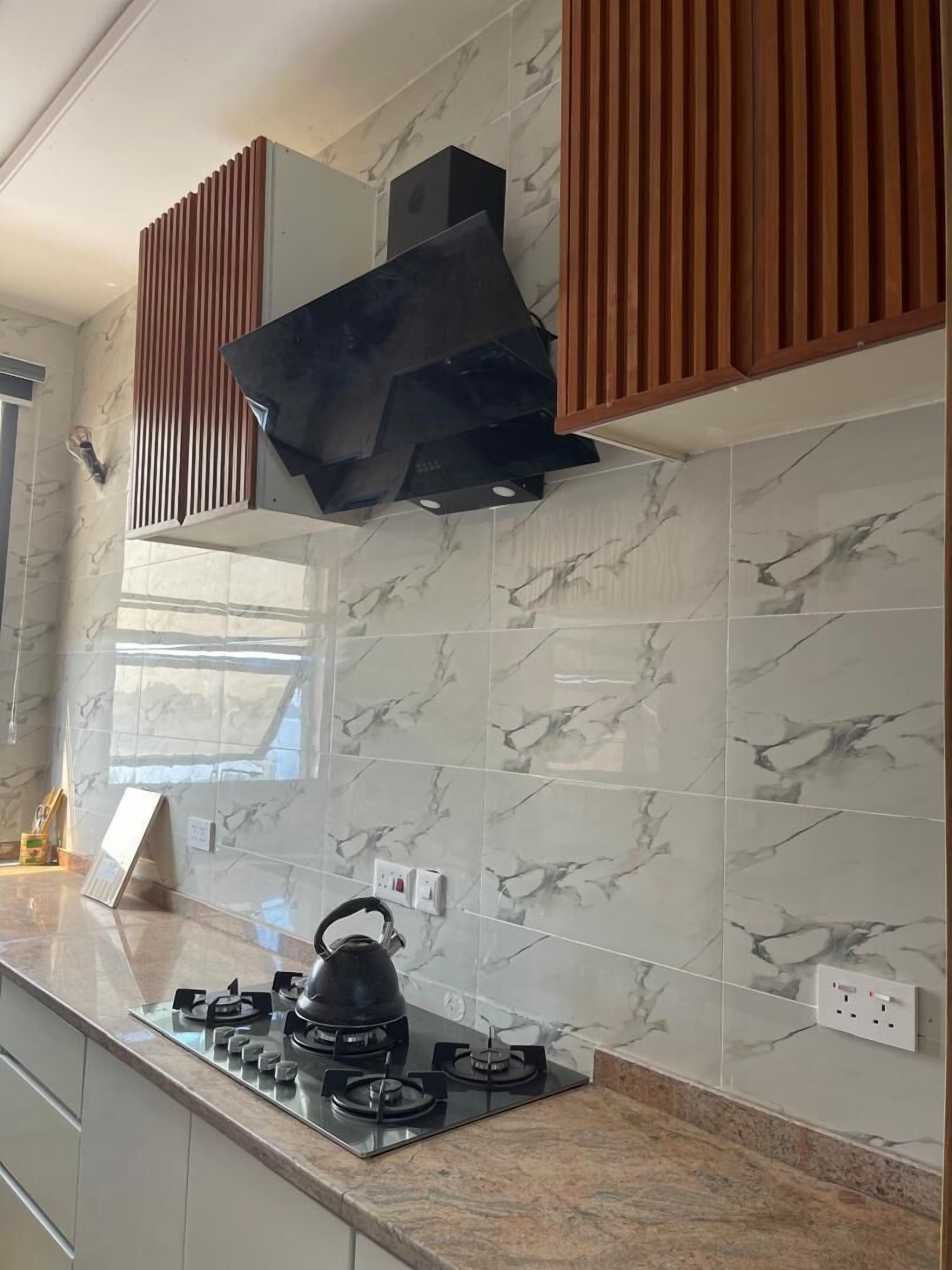 Una cocina moderna con estufa a gas, hervidor y extractor de humos.