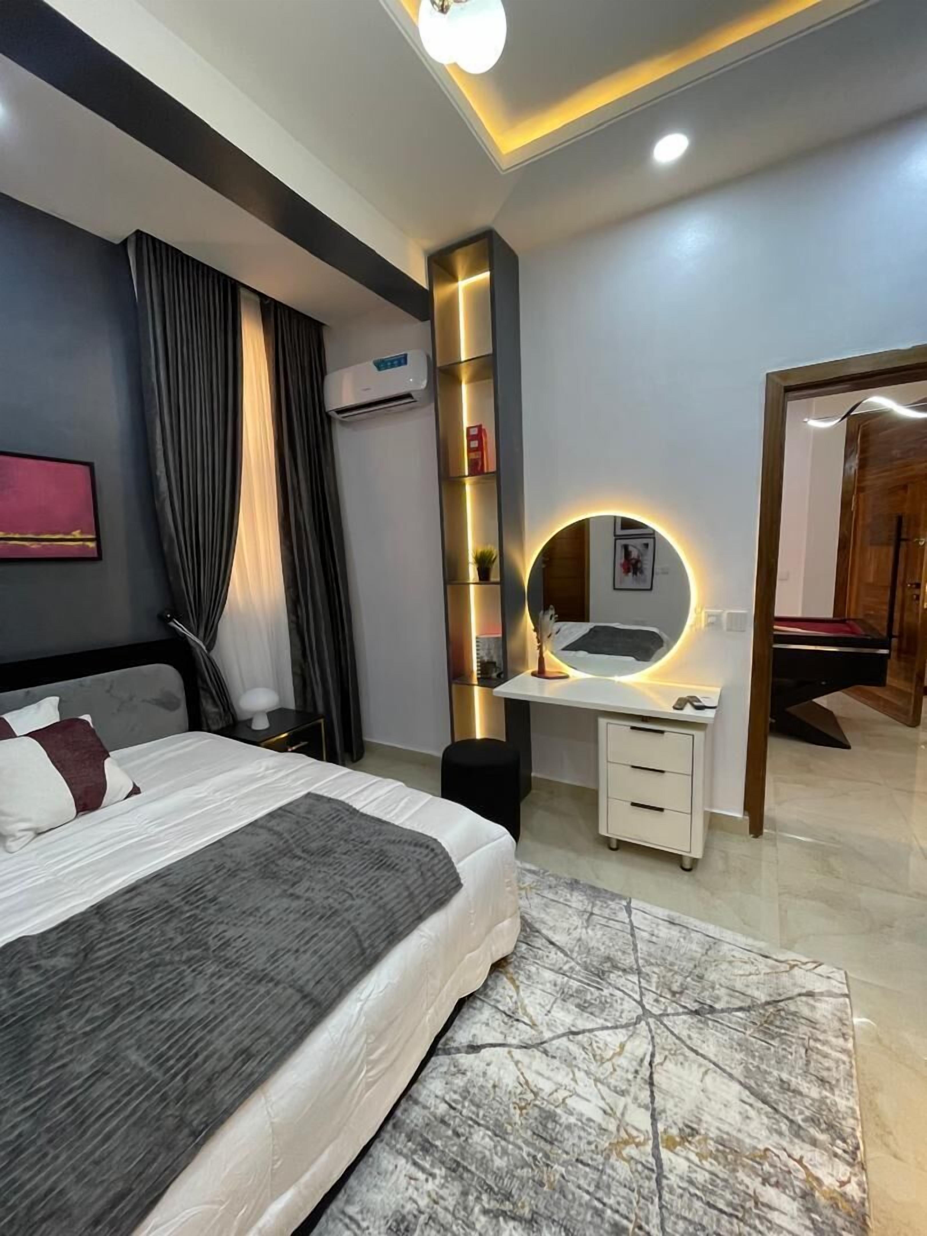Un dormitorio moderno con cama, mesita de noche, escritorio y espejo.