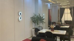 A modern dining area with a black sofa, a dining table, and a chandelier. - Spacious 2-bedroom apartment (Lekki)