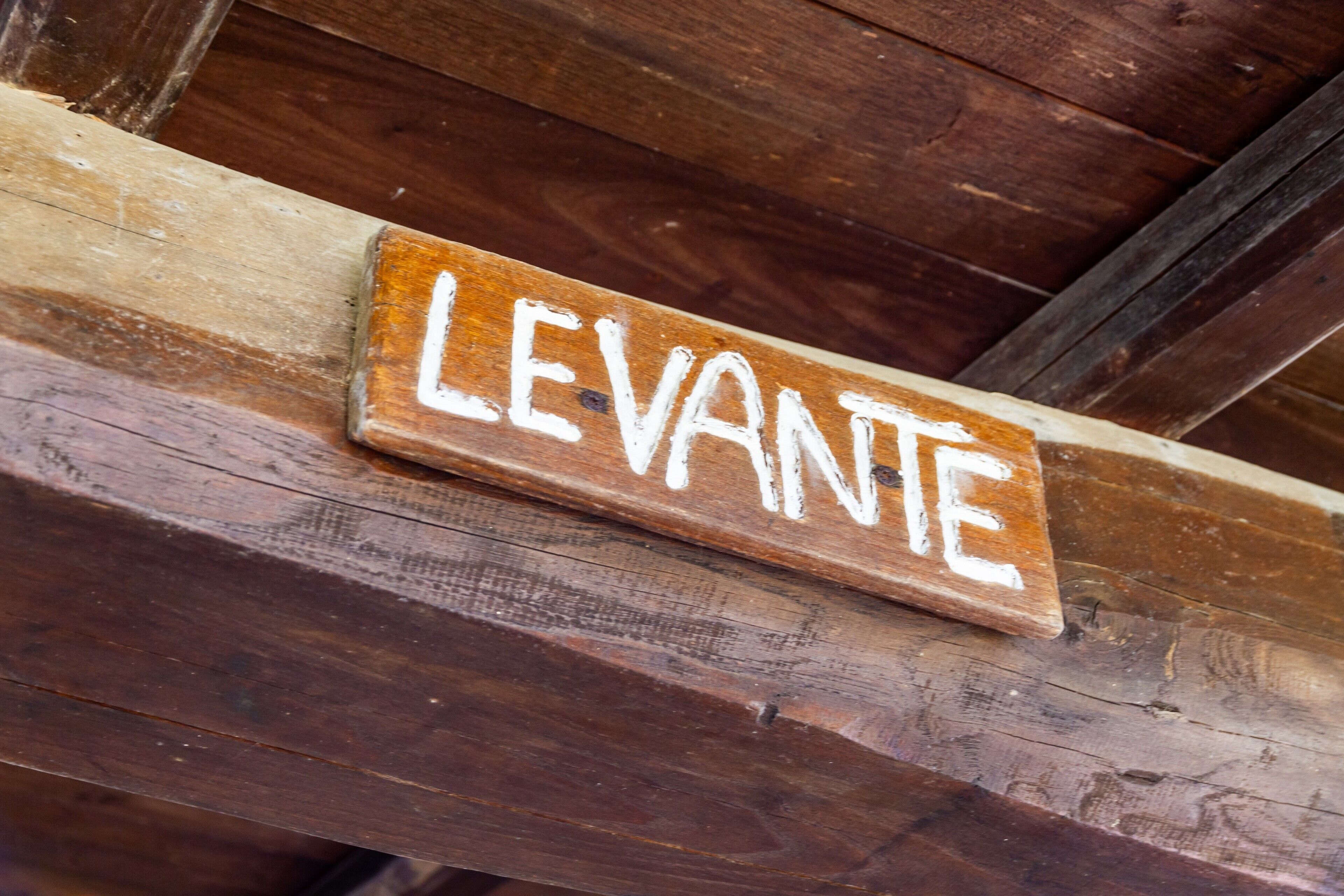 Un senyal de fusta amb la paraula 'LEVANTE' escrita sobre una biga de fusta rústica.