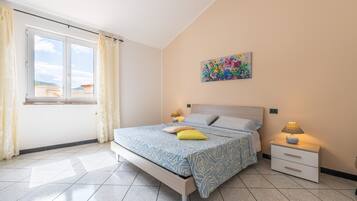 Une chambre à coucher avec un lit, des tables de chevet, une fenêtre et un tableau au mur.