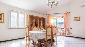 Un comedor con una mesa dispuesta para cuatro, un armario de madera y vistas a través de un ventanal.