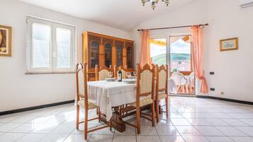 Un coin repas avec une table dressée pour quatre personnes, un buffet en bois et une vue à travers une porte vitrée.