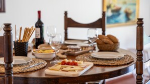Una mesa de comedor dispuesta con platos, vasos, una botella de vino y diversos alimentos.