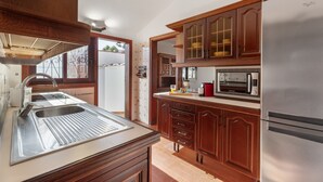 Una cocina con armarios de madera, un refrigerador de acero inoxidable, un microondas y un lavamanos.