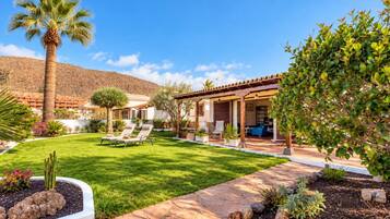 Propiedad residencial con patio, mobiliario exterior y césped bien cuidado.