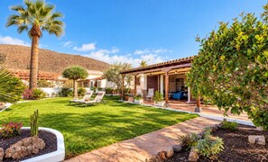 A residential property with a patio area, outdoor seating, and a well-maintained lawn.