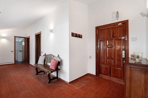 A hallway with a bench, a wooden door, and a wall-mounted light fixture.