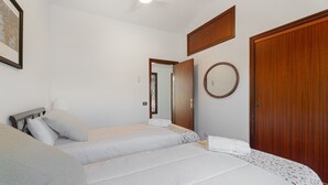 Un dormitorio con dos camas, un armario de madera, un espejo y un cuadro en la pared.