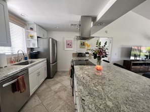 A modern kitchen with granite countertops, stainless steel appliances, and a dining area with a TV.