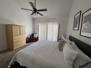 A bedroom with a bed, a wardrobe, a chair, a window with curtains, and a ceiling fan. - Beautiful Southwest Facing 2 Bedroom on the Greenbelt! (Palm Desert)