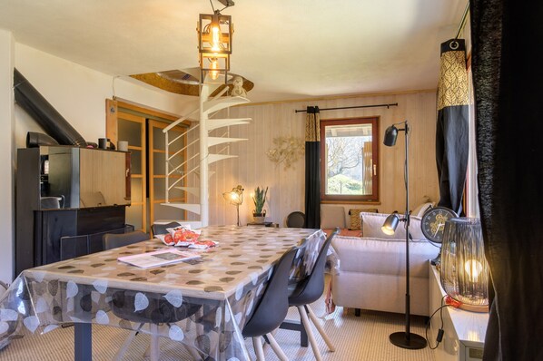 A dining area with a table, chairs, a chandelier, a sofa, and a lamp.