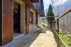 A wooden exterior with a balcony, a door, and a view of a mountainous landscape.