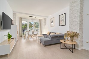 A modern living room with a grey sofa, a wooden coffee table, and a TV mounted on the wall.