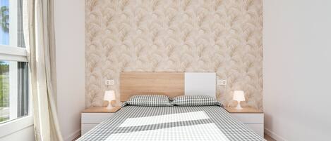 A bedroom with a checkered bedspread, a wooden headboard, bedside lamps, and a window with curtains.