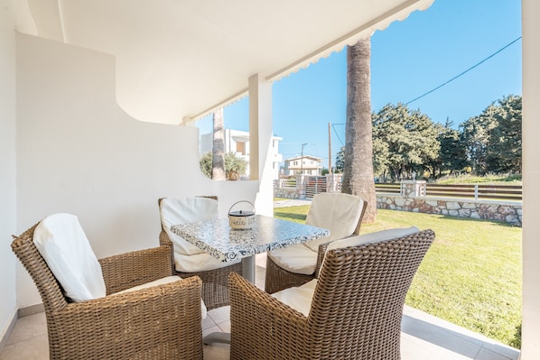 A covered outdoor seating area with wicker furniture and a patterned table.