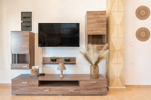 A modern living room with a flat-screen TV, wooden entertainment unit, and decorative wall art.