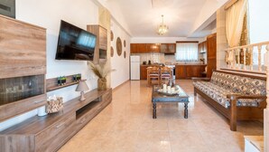 A spacious living area with a TV, sofa, and dining table. - Studio 'Fanes 3' with Mountain View, Wi-Fi and Air Conditioning (Rhodes)