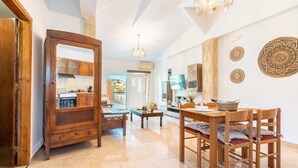 A spacious kitchen with wooden cabinets, a dining table with chairs, and a chandelier. - Studio 'Fanes 3' with Mountain View, Wi-Fi and Air Conditioning (Rhodes)