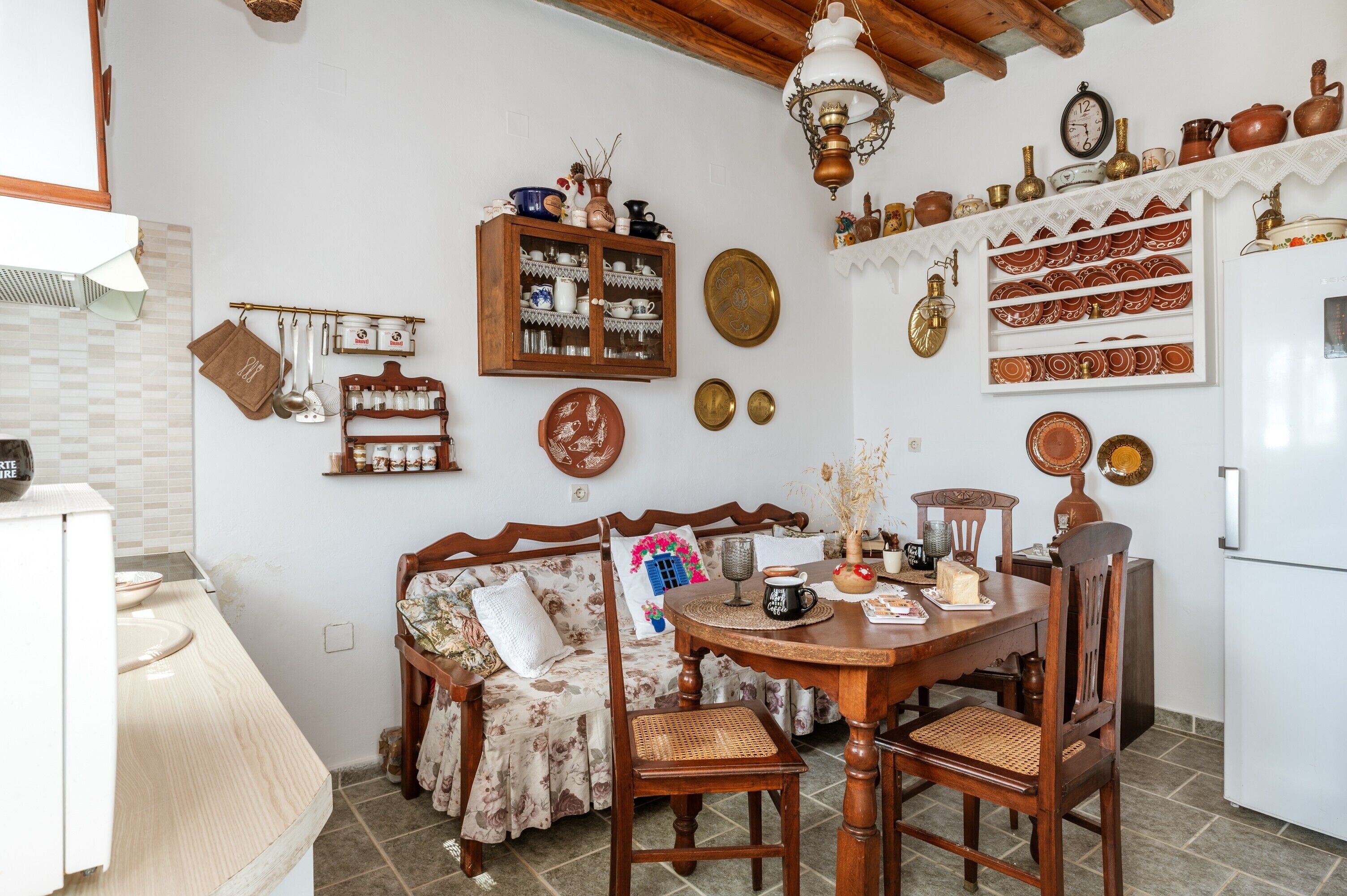 A kitchen with a dining table, chairs, a wooden cabinet, and various kitchen utensils.