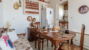 Un coin repas comprenant une table en bois, des chaises, un réfrigérateur et des objets décoratifs accrochés aux murs.