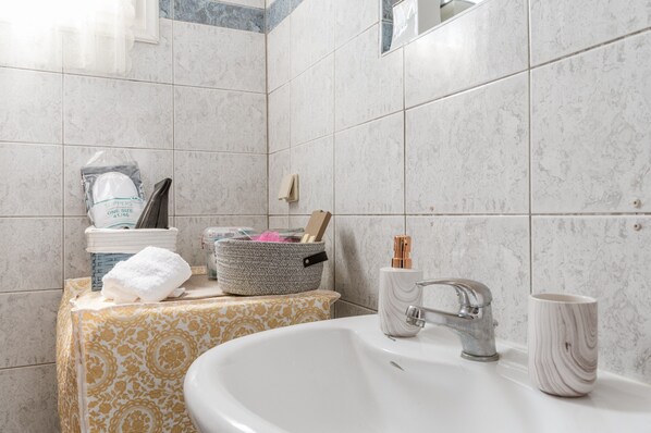 A bathroom with a sink, mirror, and toiletries.