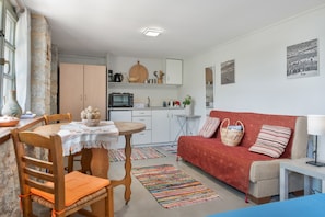 Un espacio habitable compacto con comedor, kitchenette y un sofá rojo.