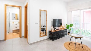 Een moderne woonkamer met een televisie, een salontafel en een plant.