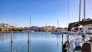 Un puerto deportivo con barcos amarrados, agua tranquila y edificios al fondo.