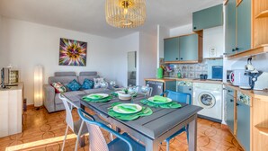 Una cocina compacta con comedor, lavadora y sofá.