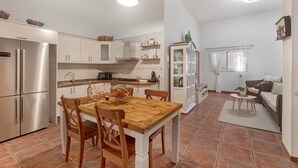 A modern kitchen with white cabinets, a wooden dining table, and a built-in oven. - Holiday Apartment 'Casa Eusebia' with Wi-Fi (Arona)