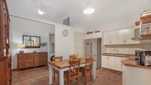A kitchen with white cabinets, a wooden dining table, and a refrigerator. - Holiday Apartment 'Casa Eusebia' with Wi-Fi (Arona)