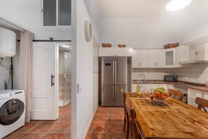 Una cocina compacta con mesa, lavadora y refrigerador.