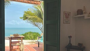 A room with a bed, a table with chairs, a view of the sea, and a sign on the wall. - Pousada Vila Matury (Icapuí)