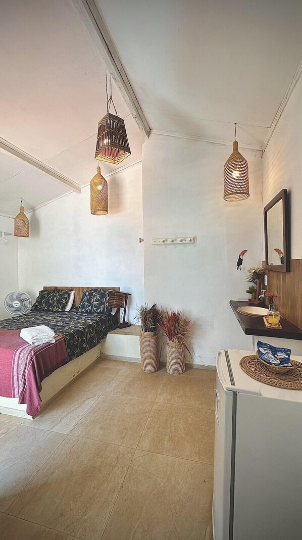 A bedroom with a bed, bedside tables, a mirror, and hanging lights.